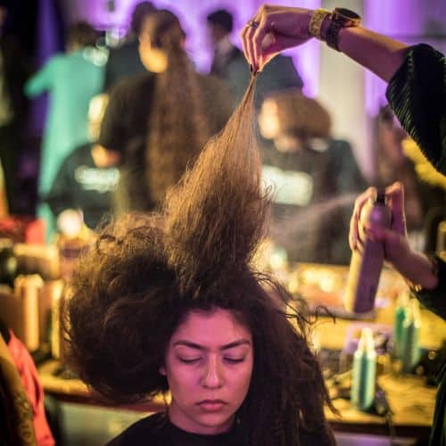 Stylist spraying product while teasing a client's voluminous hair at an Omaha hair salon.