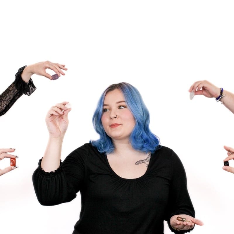 A woman with blue hair, styled at an Omaha hair salon, is surrounded by multiple hands with different gestures against a white background.