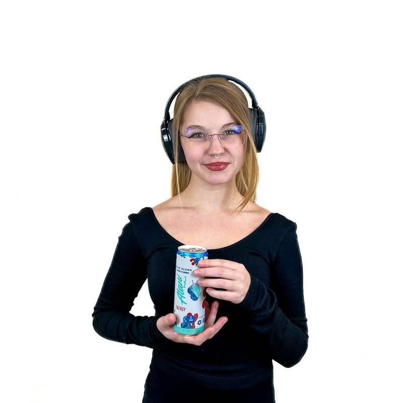 A person wearing headphones holds a can with both hands, smiling slightly.