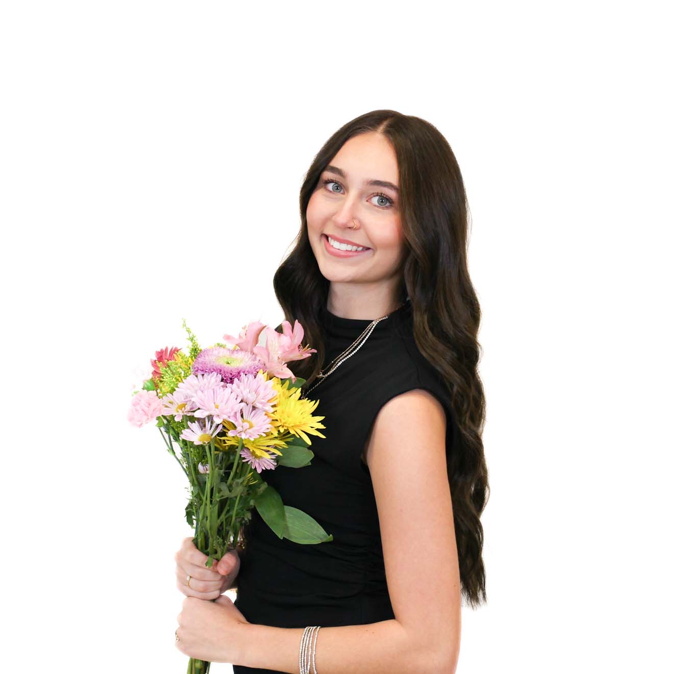 Woman with long dark hair wearing a sleeveless black top holds a bouquet of colorful flowers and smiles against a plain white background.