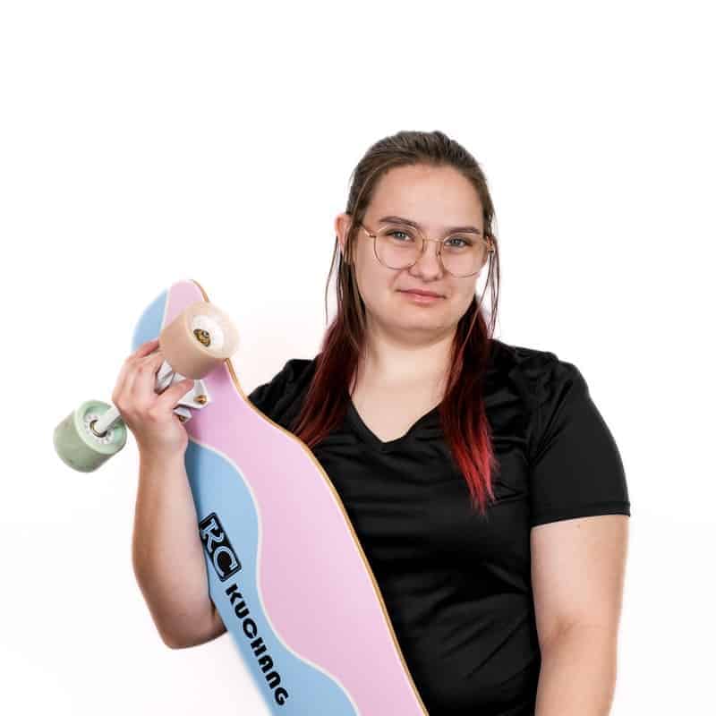 Woman holding a skateboard outside a cosmetology school.