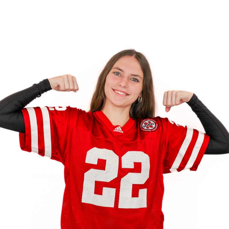 A person wearing a red football jersey with the number 22 poses with arms flexed.