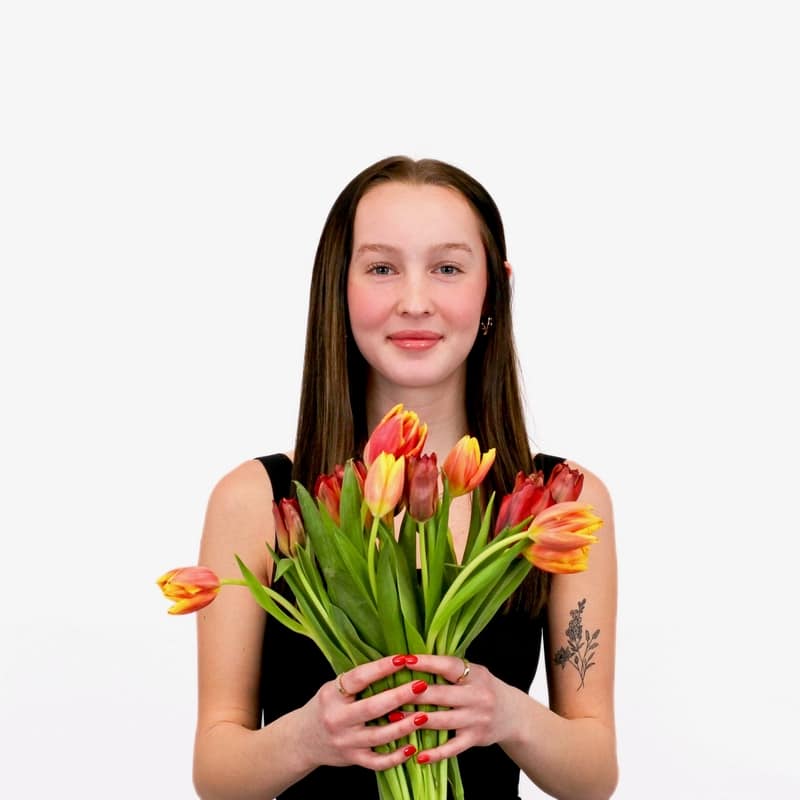 A smiling woman holding a bouquet of tulips against a white background in Omaha.