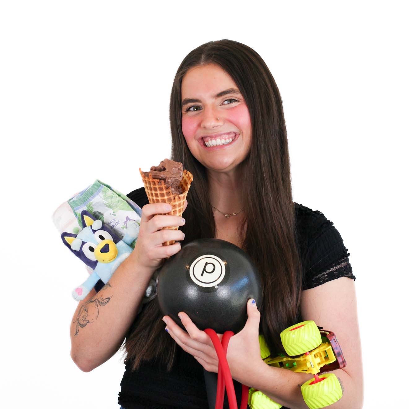 A woman with long brown hair holds a chocolate ice cream cone, a pair of socks with a cartoon character, a black exercise weight with a red band, and yellow roller skates.