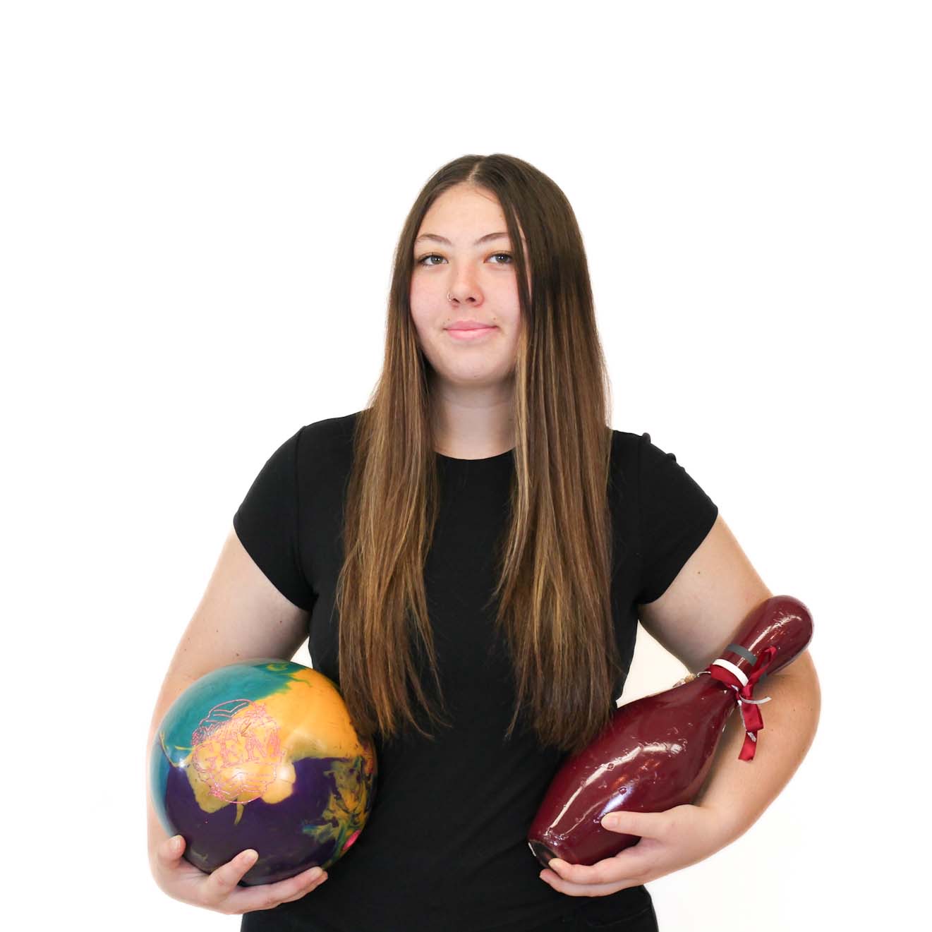 A woman with long brown hair in a black shirt holds a bowling ball in one hand and a large maroon bowling pin in the other, standing against a white background.