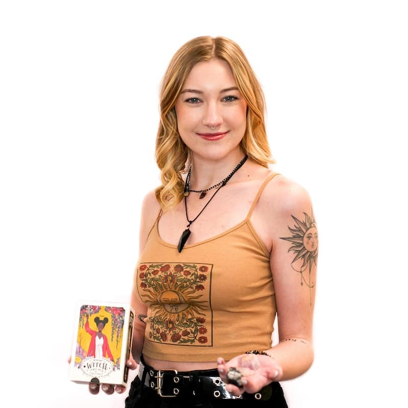 A woman with a sunflower tattoo on her arm holding tarot cards in a hair salon.
